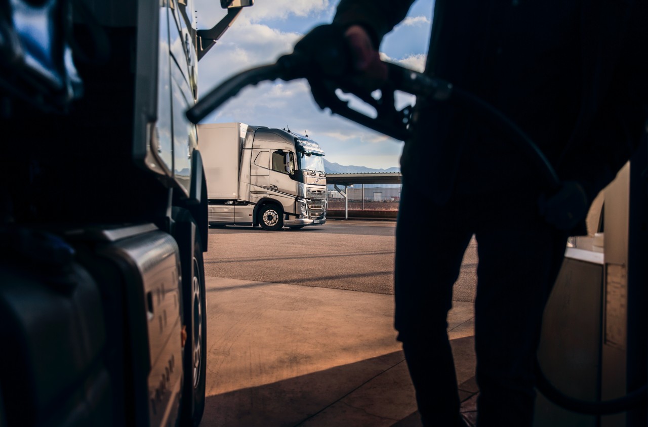 Sjåfør som fyller drivstoff på en lastebil, foran en Volvo lastebil. 